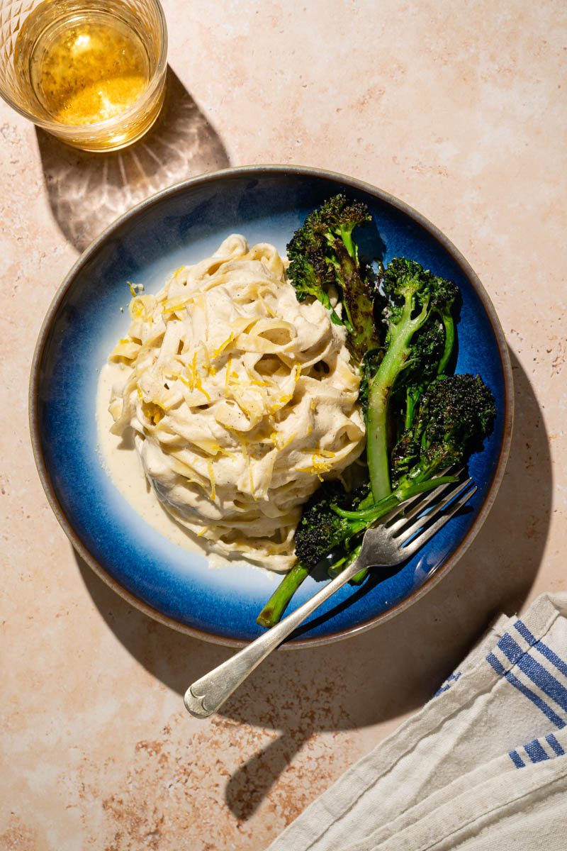 creamy lemon and broccoli pasta in sun with glass