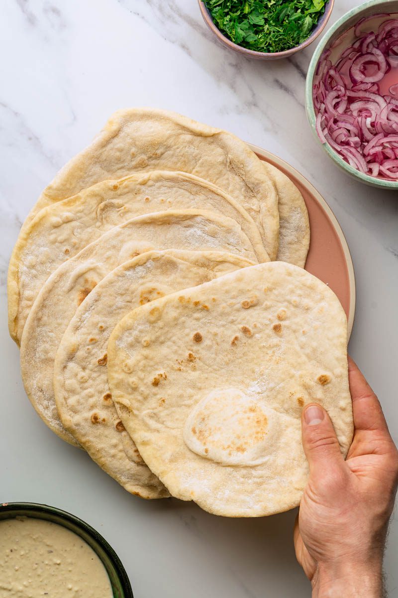 homemade flatbreads with person grabbing a flatbread at an angle