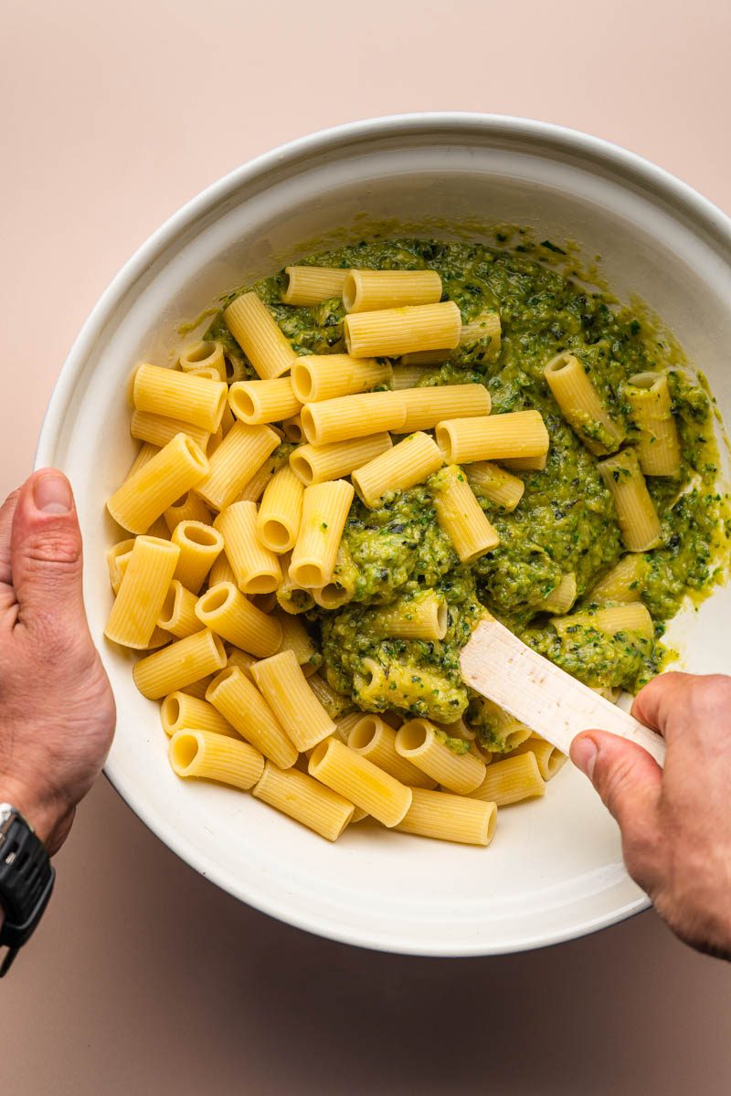 mixing courgette pesto in bowl with pasta